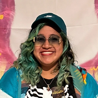 Portrait of Lori smiling, with a hat an sunglasses.