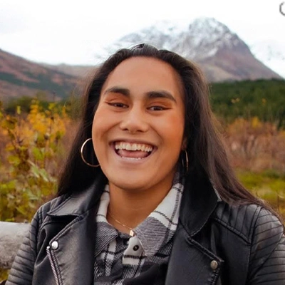 Portrait of Nalani with a big smile and mountains and nature in the background.