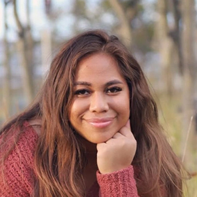 Portrait of Tala Ianu ouside full of trees and green background.